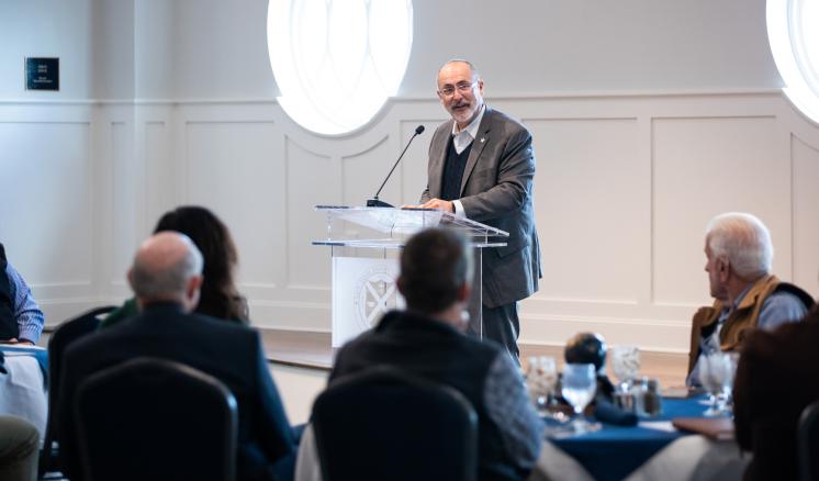 A man standing behind a podium speaking to a crowd inside
