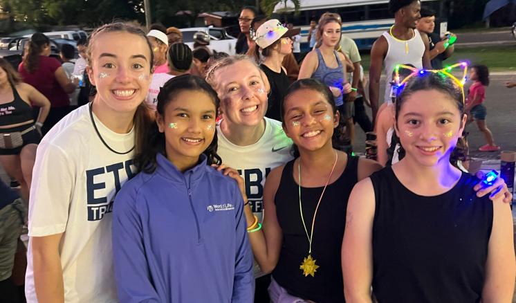 a group of college students standing together outside with children