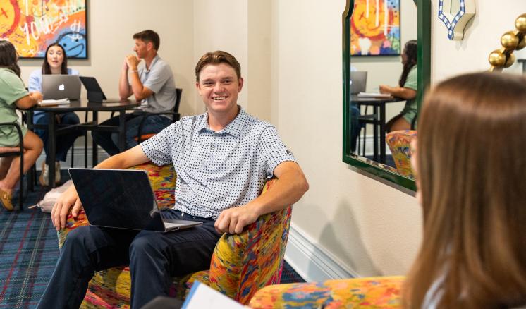 Students sitting on chairs with computers talking