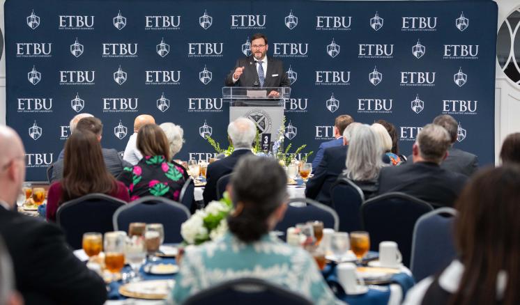 A man addressing a large crowd from behind a podium