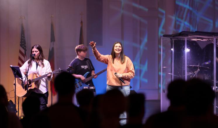 A group of people singing on a stage with a large crowd