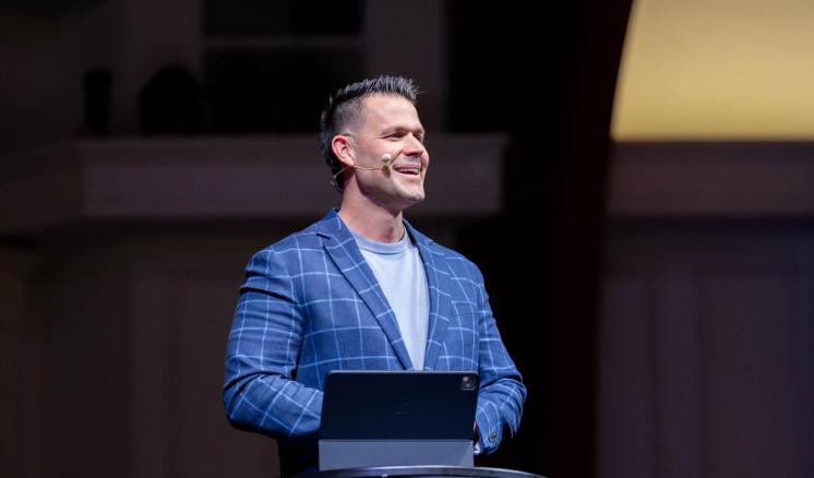 A man standing behind a podium speaking to a crowd inside