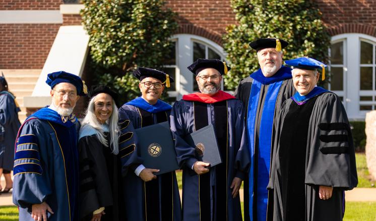 People standing outside in academic regalia holding degrees