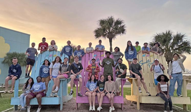 A group of people sat outside together in giant chairs on the beach