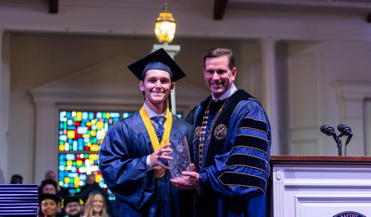 Two men in navy regalia with a crystal award.
