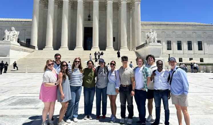 A group of students standing in front of the Supreme Court.