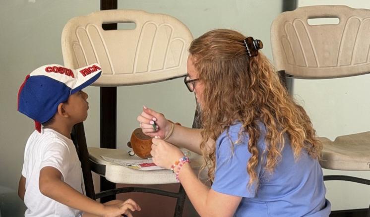 A young female nurse taking notes on a little boy in a blue and white ballcap.
