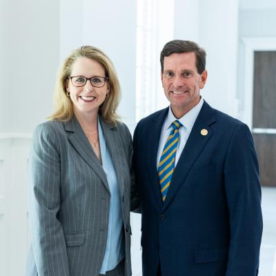 Two people stood in a brightly lit room wearing formal clothing smiling