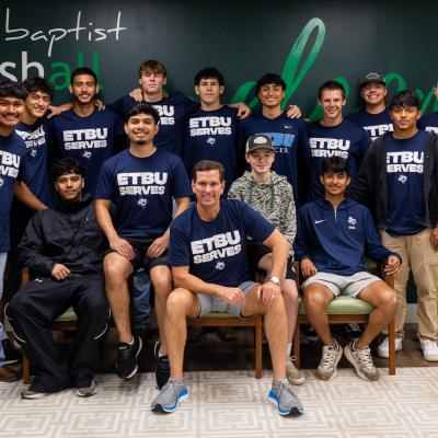 A group of students posing for a group photo in front of a first baptist sign