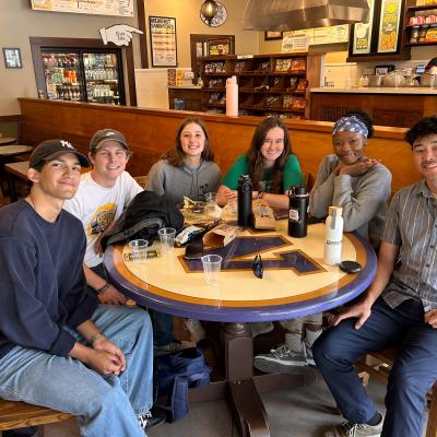 A group of people seated at a table smiling with beverages upon it