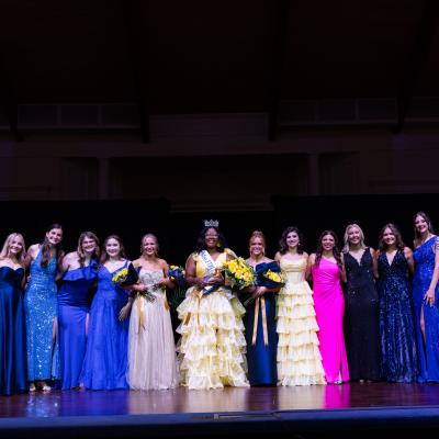 A group of women standing on a stage in formal attire