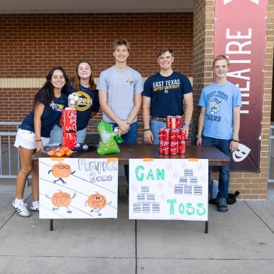 A group of people stood over a fall festival table outside