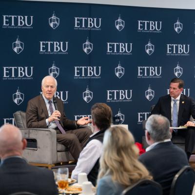 2 men sitting on a stage for a Q&A taking questions. Dressed in professional attire