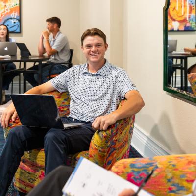 Students sitting on chairs with computers talking