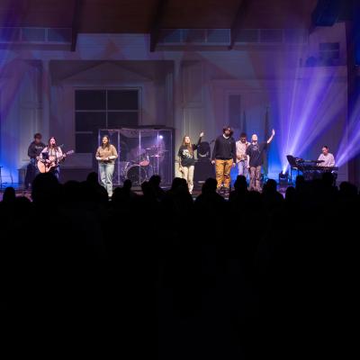 A group of people singing on a stage with a large crowd