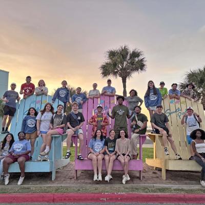 A group of people sat outside together in giant chairs on the beach
