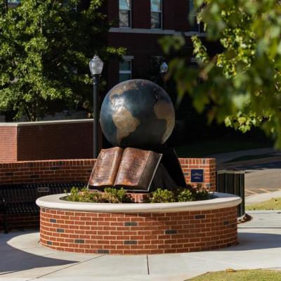 A bronze globe statue with a Bible underneath.
