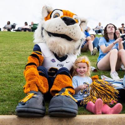 Tiger mascot and young girl smiling at camera 