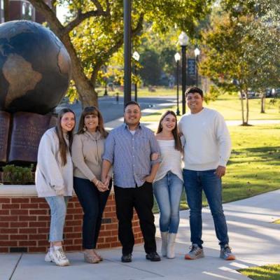 Family standing in front on bronze globe statue