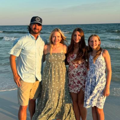 Four people standing on a beach with the ocean in the background.
