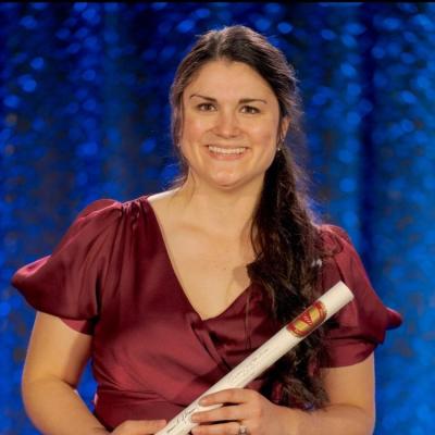 A woman posing in front of a blue backdrop in formal clothing