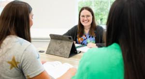 Female students sitting at desks with study materials laughing and talking.