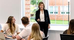 Professor teaching while standing in front of students seated in desks.