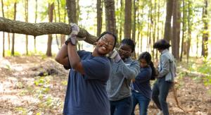 Students carrying a large limb on for a service project.