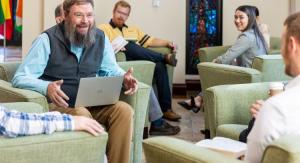 Students and professors sitting in chairs talking and studying with laptops and textbooks.