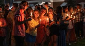 Students holding lit candles at night time.