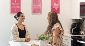 Two female students talking at a kitchen island.