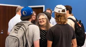 An older woman talking to two students