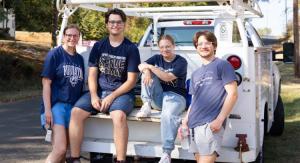 four students sitting on the back of a truck