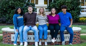 five students sitting on a wall infront of a light
