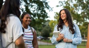 Group of girls talking outside on a green lawn.