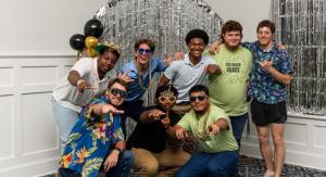 People posing for a photo indoors in front of a shiny silver backdrop