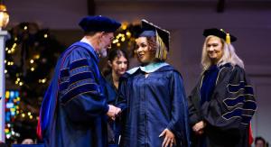 people in academic regalia on stage shaking hands