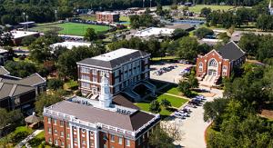 Aerial view of a ETBU's campus with brick buildings, tree-lined paths, and surrounding greenery on a sunny day.