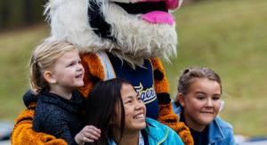 Kids smiling with Tabby the TIger Mascot on a football field