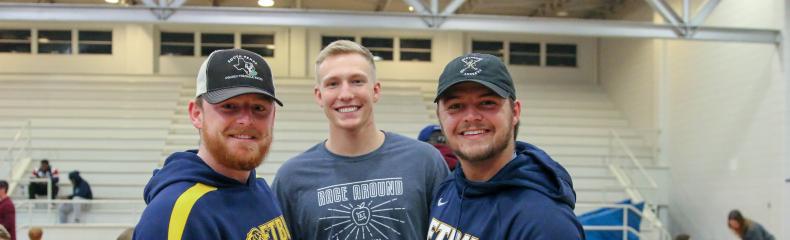 Three male student-athletes show the OCC boxes they put together