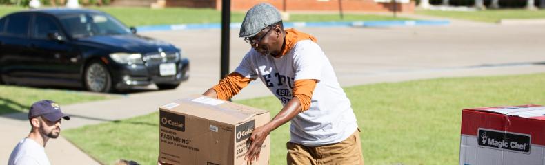 People unloading boxes from a truck in a residential area.