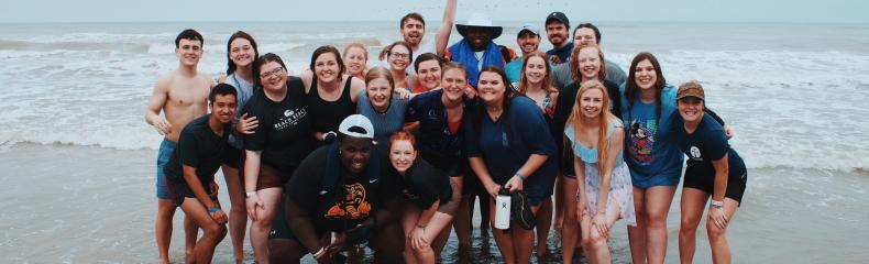 Group of students on the beach smiling at the camera