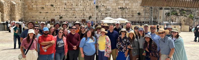 A group of people smiling at the camera with ruins in the background