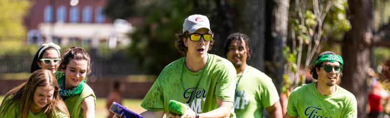 Male and females outside grabbing sponges out of a trash can of water for a game