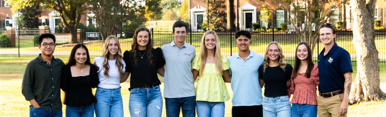 Group of male and female students smiling at the camera outdoors 