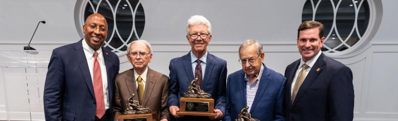 Three men holding awards in the center with two men on either side smiling at the camera