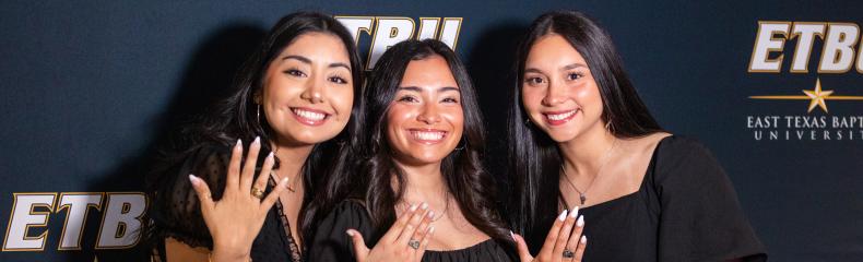 Three senior students show off their rings at ETBU's ring blessing ceremony