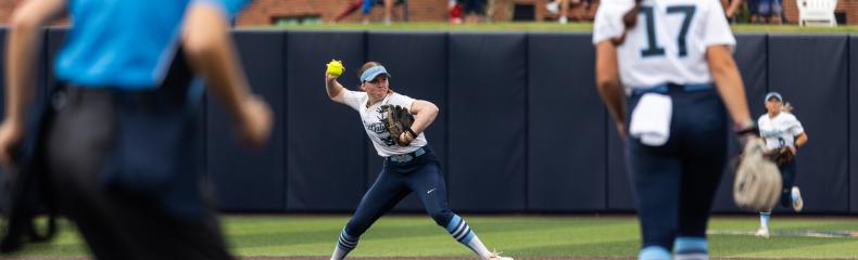 A female shortstop softball player throwing a softball from outfield.