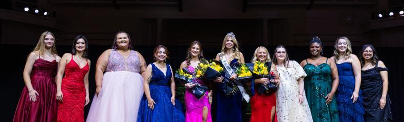 Miss ETBU 2024 Pageant participants stand next to each other on stage in formal attire.