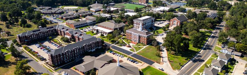 Aerial view of a university campus with various buildings and green spaces.